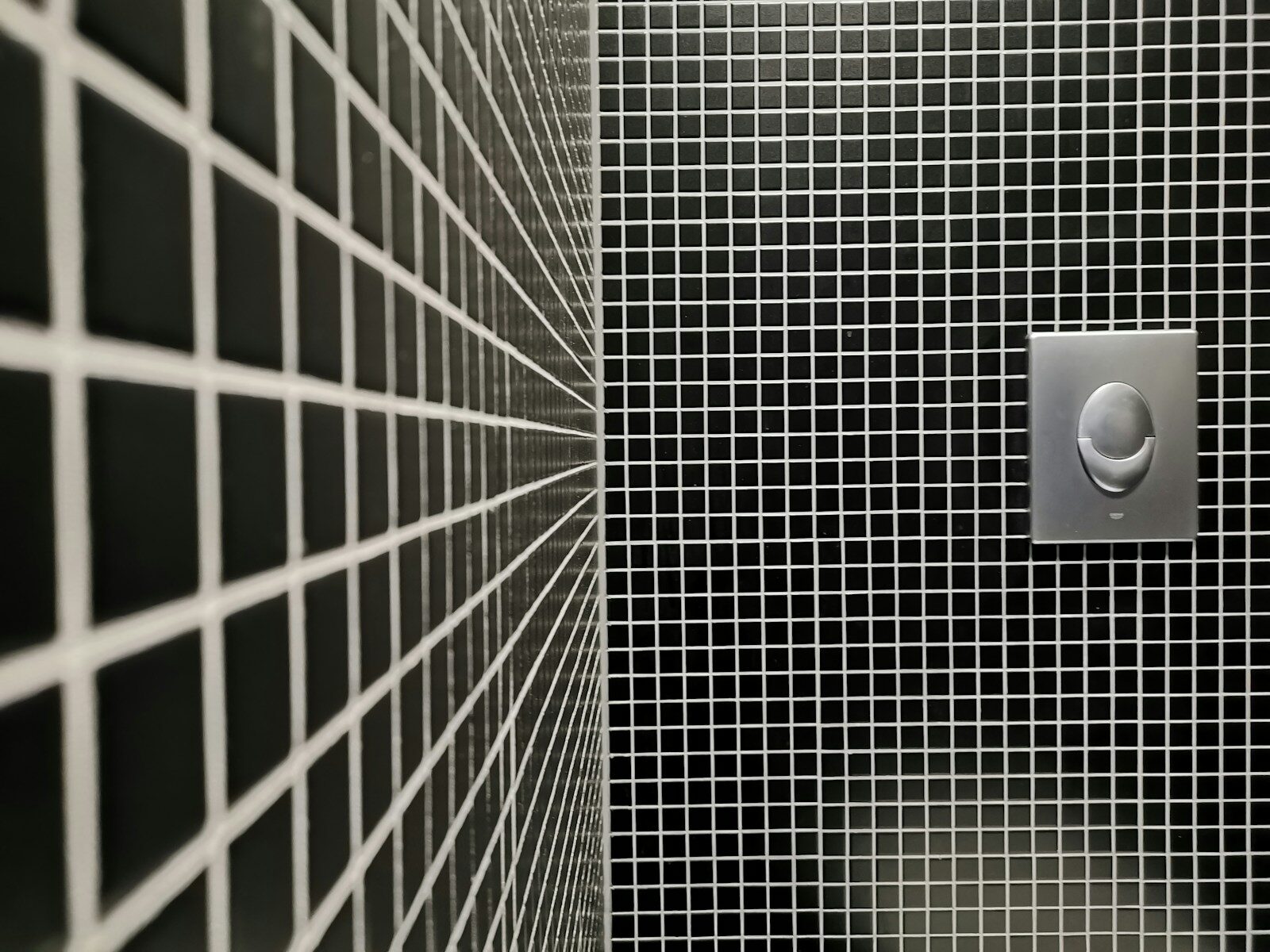 a black and white tiled bathroom with a toilet paper dispenser